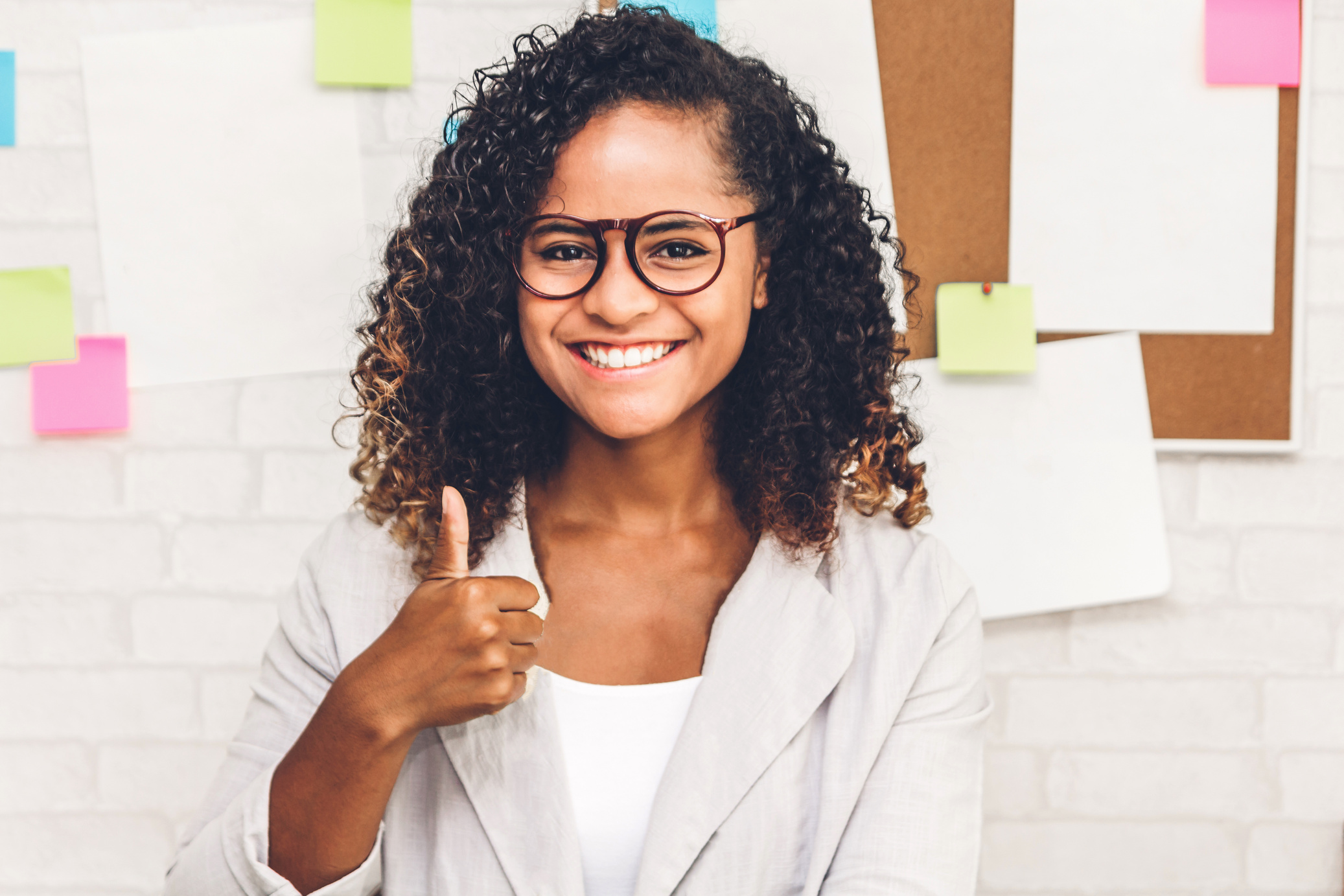 an individual in glasses giving the thumbs up sign